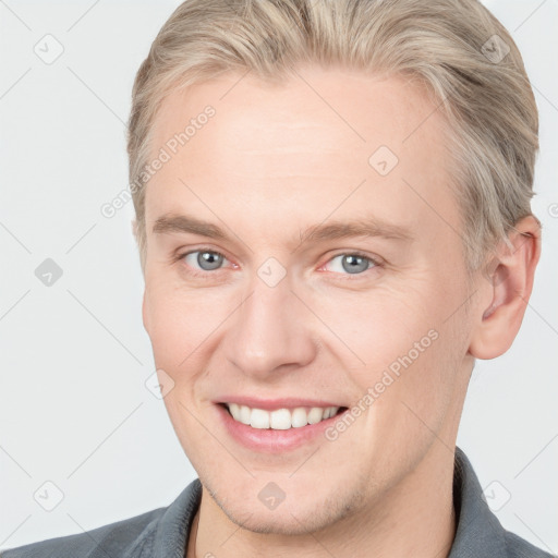 Joyful white young-adult male with short  brown hair and blue eyes