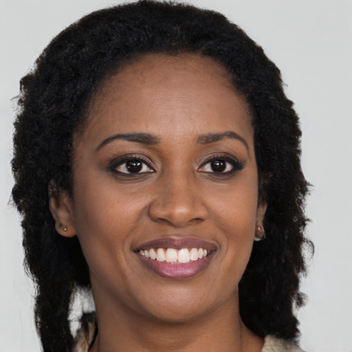 Joyful black young-adult female with long  brown hair and brown eyes