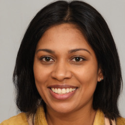 Joyful black young-adult female with long  brown hair and brown eyes