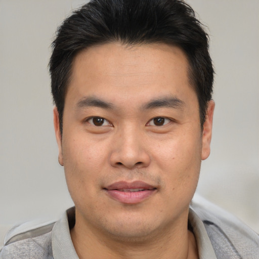 Joyful asian young-adult male with short  brown hair and brown eyes