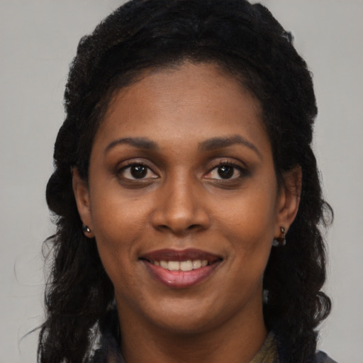 Joyful black young-adult female with long  black hair and brown eyes