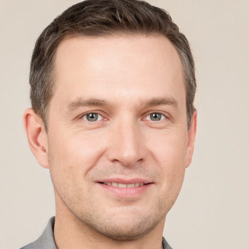 Joyful white young-adult male with short  brown hair and grey eyes