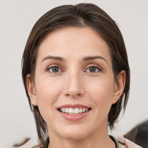 Joyful white young-adult female with medium  brown hair and grey eyes