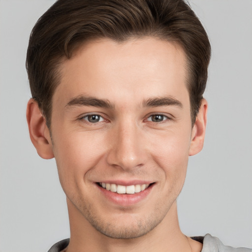 Joyful white young-adult male with short  brown hair and grey eyes