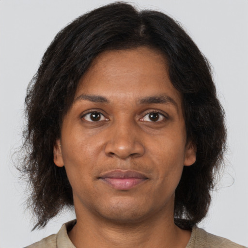 Joyful black young-adult female with long  brown hair and brown eyes