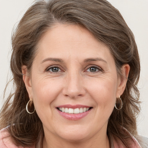 Joyful white adult female with long  brown hair and grey eyes