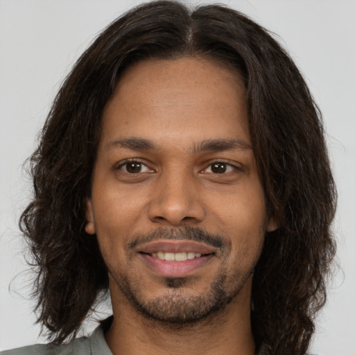 Joyful black young-adult male with long  brown hair and brown eyes