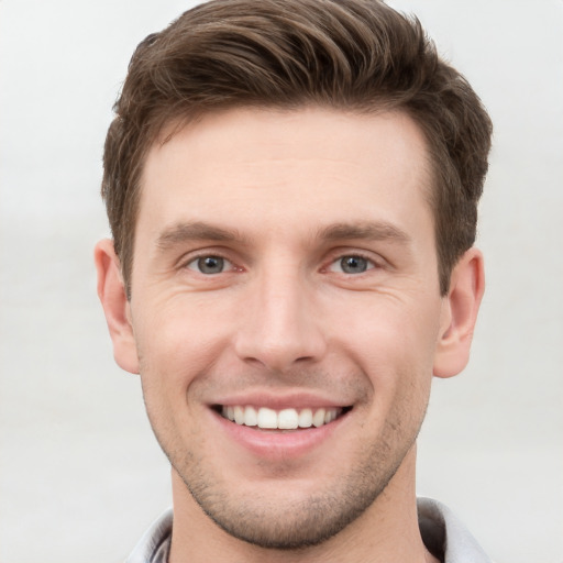 Joyful white young-adult male with short  brown hair and grey eyes