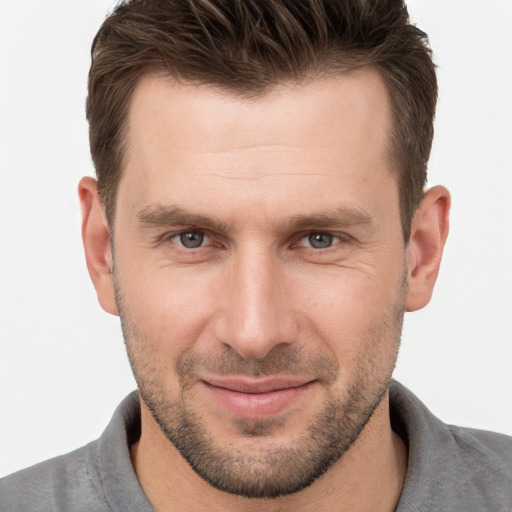 Joyful white young-adult male with short  brown hair and grey eyes