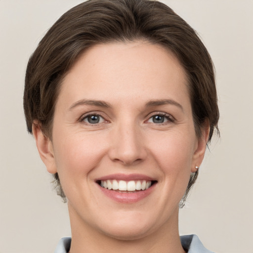 Joyful white young-adult female with short  brown hair and grey eyes