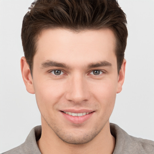 Joyful white young-adult male with short  brown hair and grey eyes