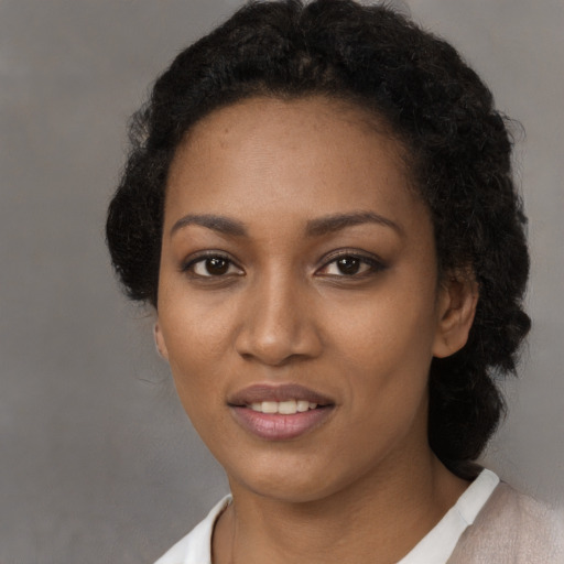 Joyful black young-adult female with short  black hair and brown eyes