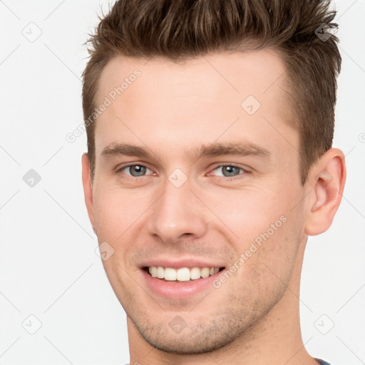 Joyful white young-adult male with short  brown hair and grey eyes