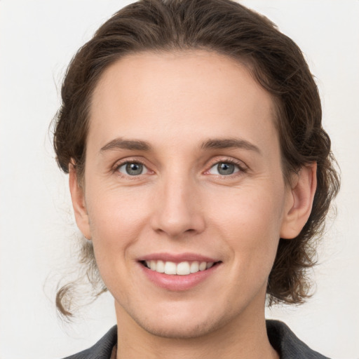 Joyful white young-adult female with medium  brown hair and grey eyes