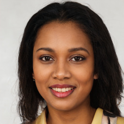 Joyful black young-adult female with long  brown hair and brown eyes