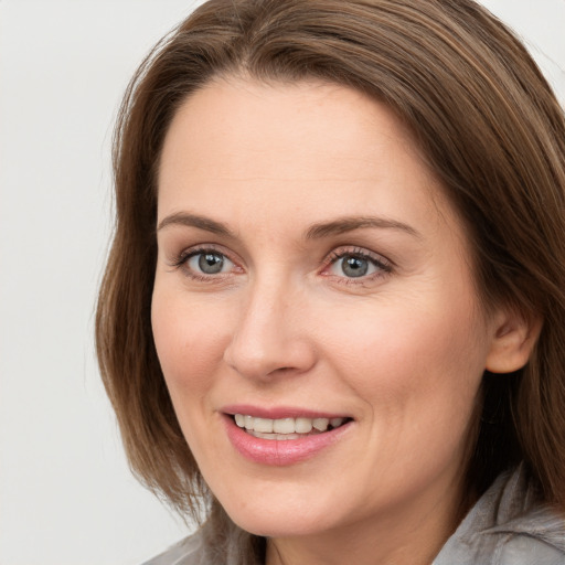 Joyful white adult female with long  brown hair and grey eyes