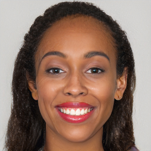 Joyful black young-adult female with long  brown hair and brown eyes