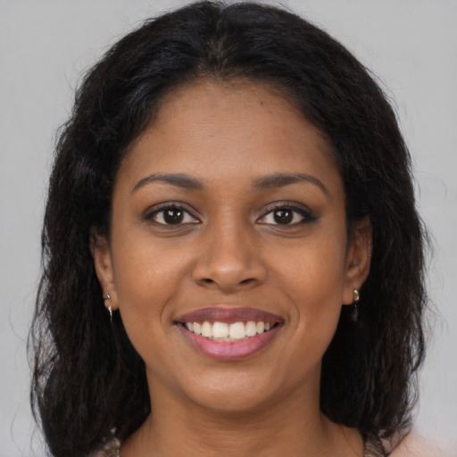 Joyful black young-adult female with long  brown hair and brown eyes