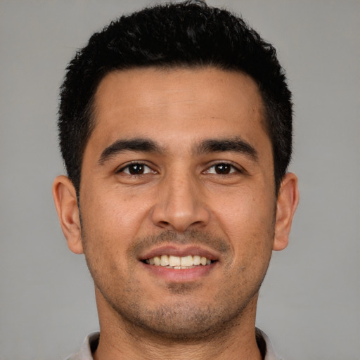 Joyful latino young-adult male with short  black hair and brown eyes