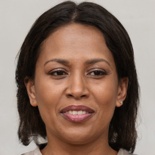 Joyful latino adult female with medium  brown hair and brown eyes