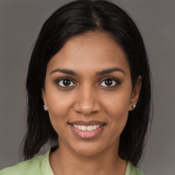 Joyful black young-adult female with long  brown hair and brown eyes