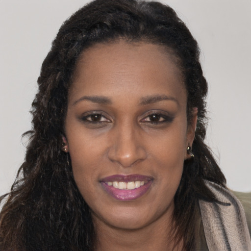 Joyful black young-adult female with long  brown hair and brown eyes