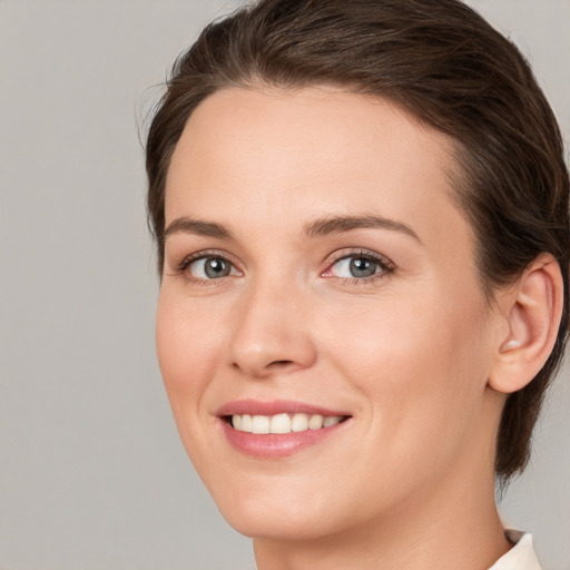 Joyful white young-adult female with medium  brown hair and grey eyes