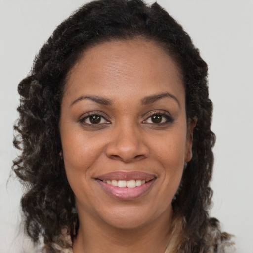 Joyful black young-adult female with long  brown hair and brown eyes