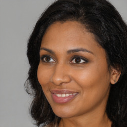 Joyful black young-adult female with long  brown hair and brown eyes