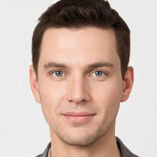 Joyful white young-adult male with short  brown hair and grey eyes