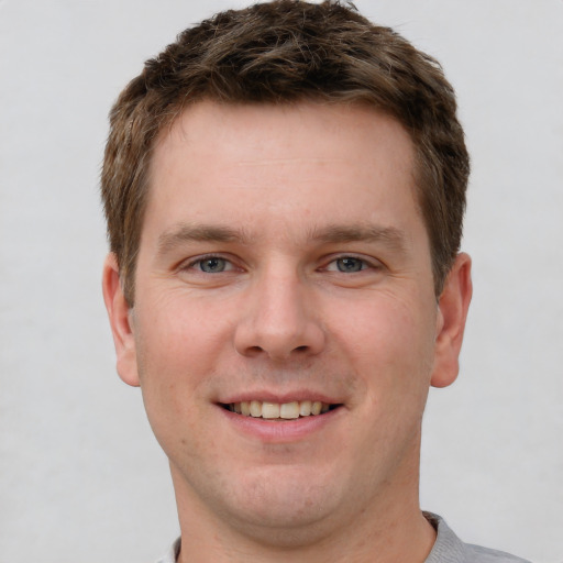 Joyful white young-adult male with short  brown hair and grey eyes