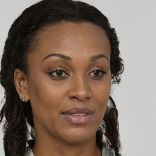 Joyful black young-adult female with long  brown hair and brown eyes