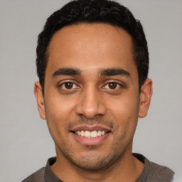 Joyful latino young-adult male with short  black hair and brown eyes