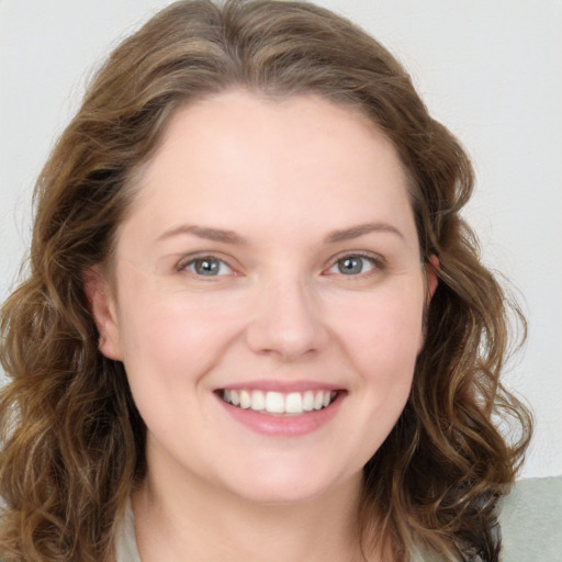 Joyful white young-adult female with long  brown hair and blue eyes