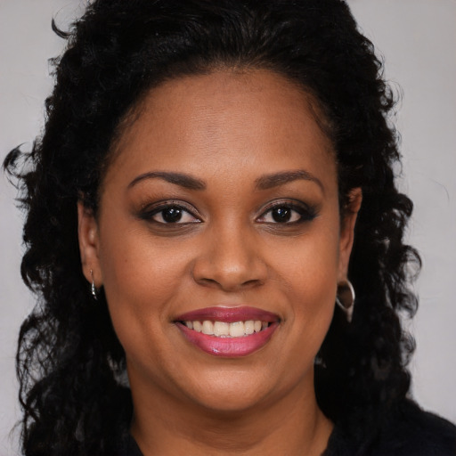 Joyful black young-adult female with long  brown hair and brown eyes