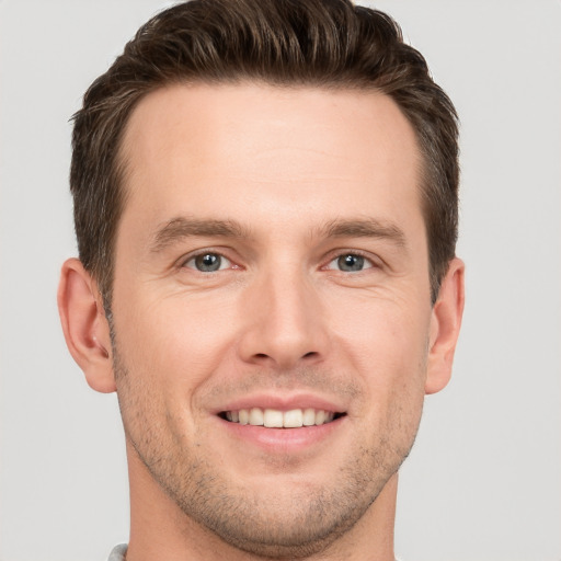 Joyful white young-adult male with short  brown hair and grey eyes