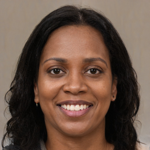 Joyful black adult female with long  brown hair and brown eyes