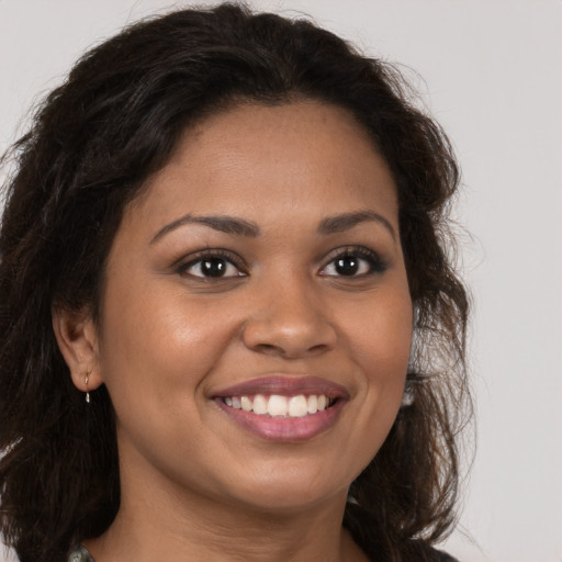 Joyful black young-adult female with long  brown hair and brown eyes