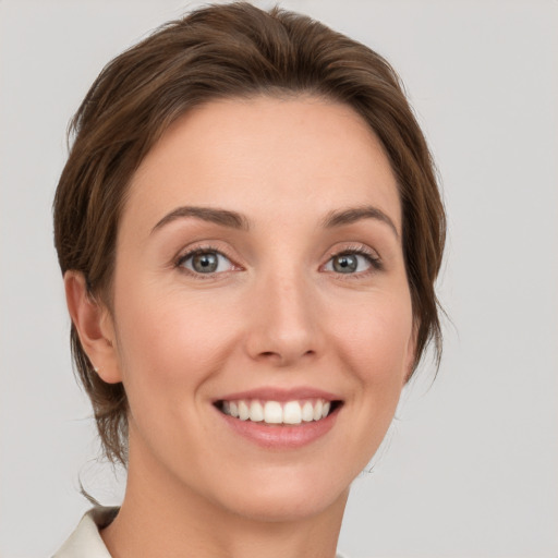 Joyful white young-adult female with medium  brown hair and grey eyes