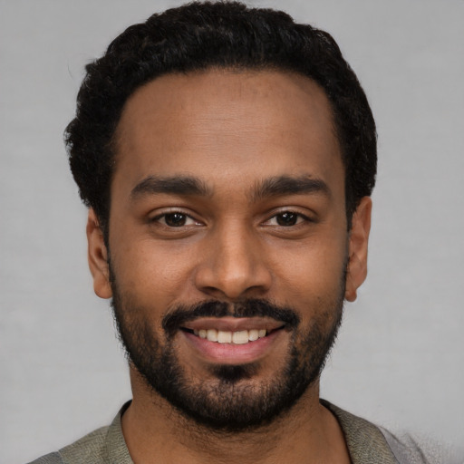 Joyful black young-adult male with short  black hair and brown eyes