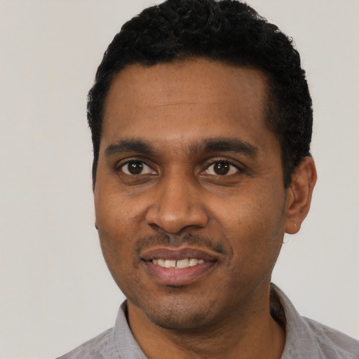 Joyful black young-adult male with short  black hair and brown eyes
