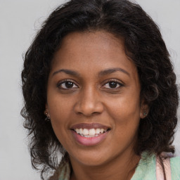 Joyful black young-adult female with long  brown hair and brown eyes