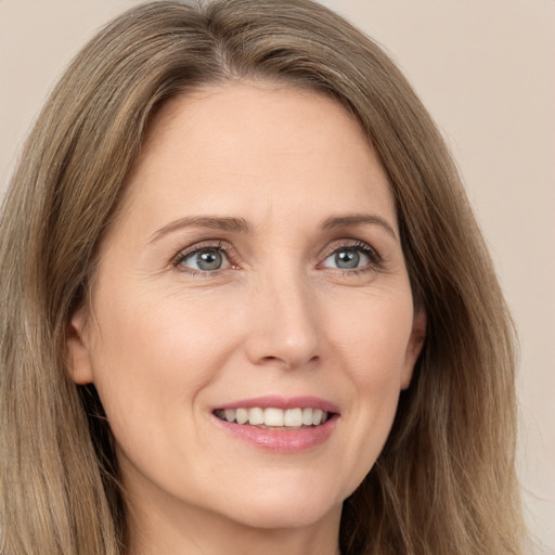 Joyful white adult female with long  brown hair and green eyes