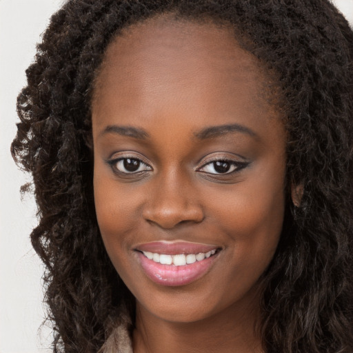 Joyful black young-adult female with long  brown hair and brown eyes