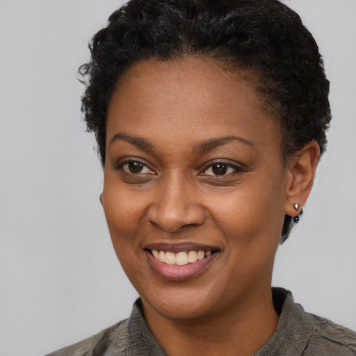 Joyful black young-adult female with short  black hair and brown eyes