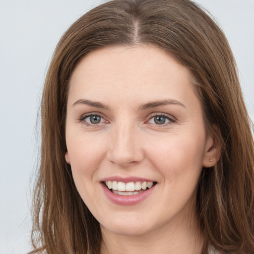 Joyful white young-adult female with long  brown hair and grey eyes