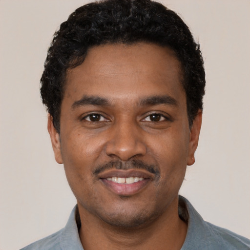 Joyful black young-adult male with short  black hair and brown eyes