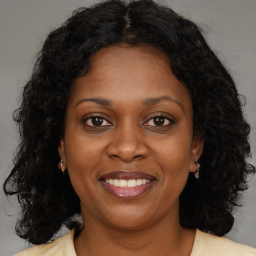 Joyful black young-adult female with long  brown hair and brown eyes
