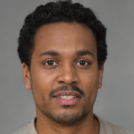 Joyful black young-adult male with short  brown hair and brown eyes