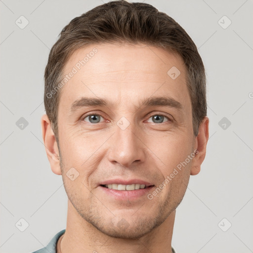 Joyful white young-adult male with short  brown hair and grey eyes